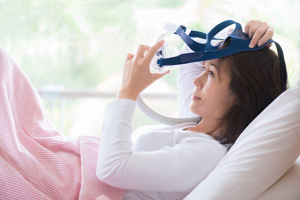 Patient with sleep apnea putting on CPAP mask