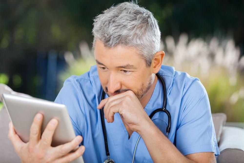 Doctor reading tablet (©TylerOlsonShutterstock.com)